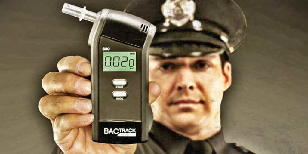 Police officer holding breathalyzer device